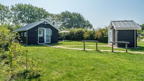 A small, dark-colored cabin with a glass door and a separate shed with a metal roof.