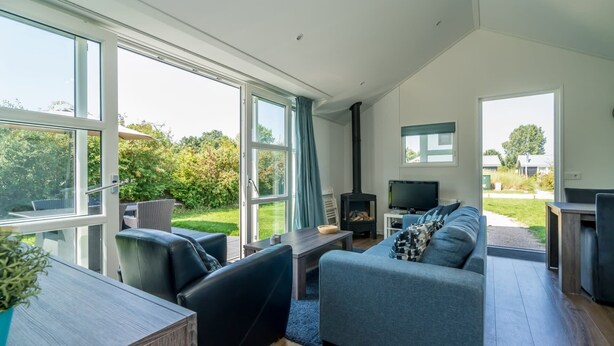 A spacious living area with a fireplace, a television, and a large window overlooking a garden.