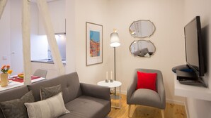 A modern living room with a grey sofa, a red chair, a floor lamp, and a flat-screen TV.