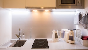 A modern kitchen with a built-in microwave, a kettle, and a coffee maker.