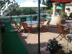 An outdoor patio area with a round table and chairs, surrounded by a wooden fence and potted plants. - Apartment in a farmhouse a few km from the center (Siena)