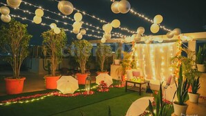 An outdoor area with string lights, balloons, and potted plants.