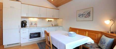 Una cocina compacta con armarios blancos, estufa y comedor con mesa y sillas.