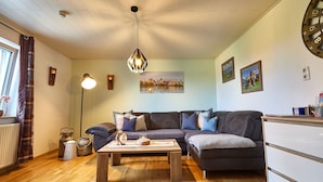 Een gezellige woonkamer met een donkergrijze bank, een houten salontafel en een hanglamp.