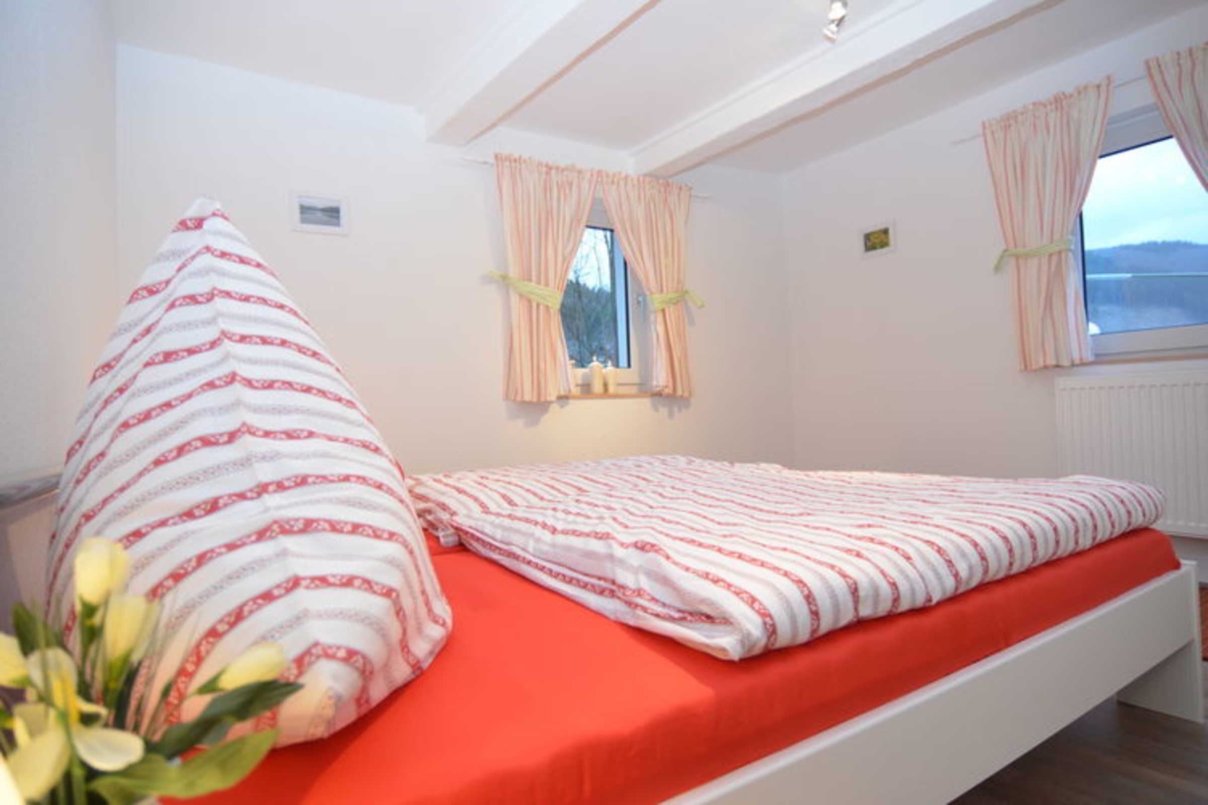 Un dormitorio con cama, ventana con cortinas y vistas al exterior.