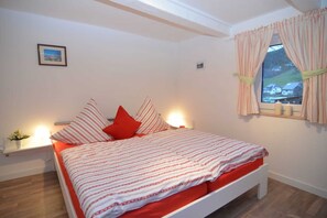 Un dormitorio con una cama, una mesita de noche, una ventana con cortinas y un cuadro en la pared.