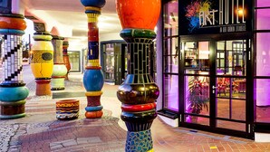 Een hotelentree met kleurrijke, uniek ontworpen pilaren en een bord waarop 'ART HOTEL' staat.