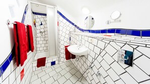 Een badkamer met witte en blauwe betegelde wanden, een witte wastafel en een douchehoek.