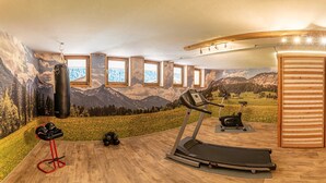Ein Heimfitnessraum mit Laufband, Ergometer, Sandsack und Trainingsgeräten.