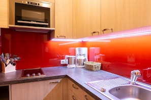 A kitchen with a built-in oven, a coffee maker, and a sink. - No. 12 Anemone - HAUS fern (Grän)