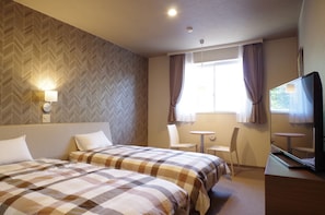 Une chambre d’hôtel avec deux lits, une télévision, une petite table et une fenêtre avec des rideaux.