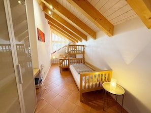 Ein Zimmer mit Etagenbett, einem kleinen Tisch und einer Treppe zu einer erhöhten Ebene.