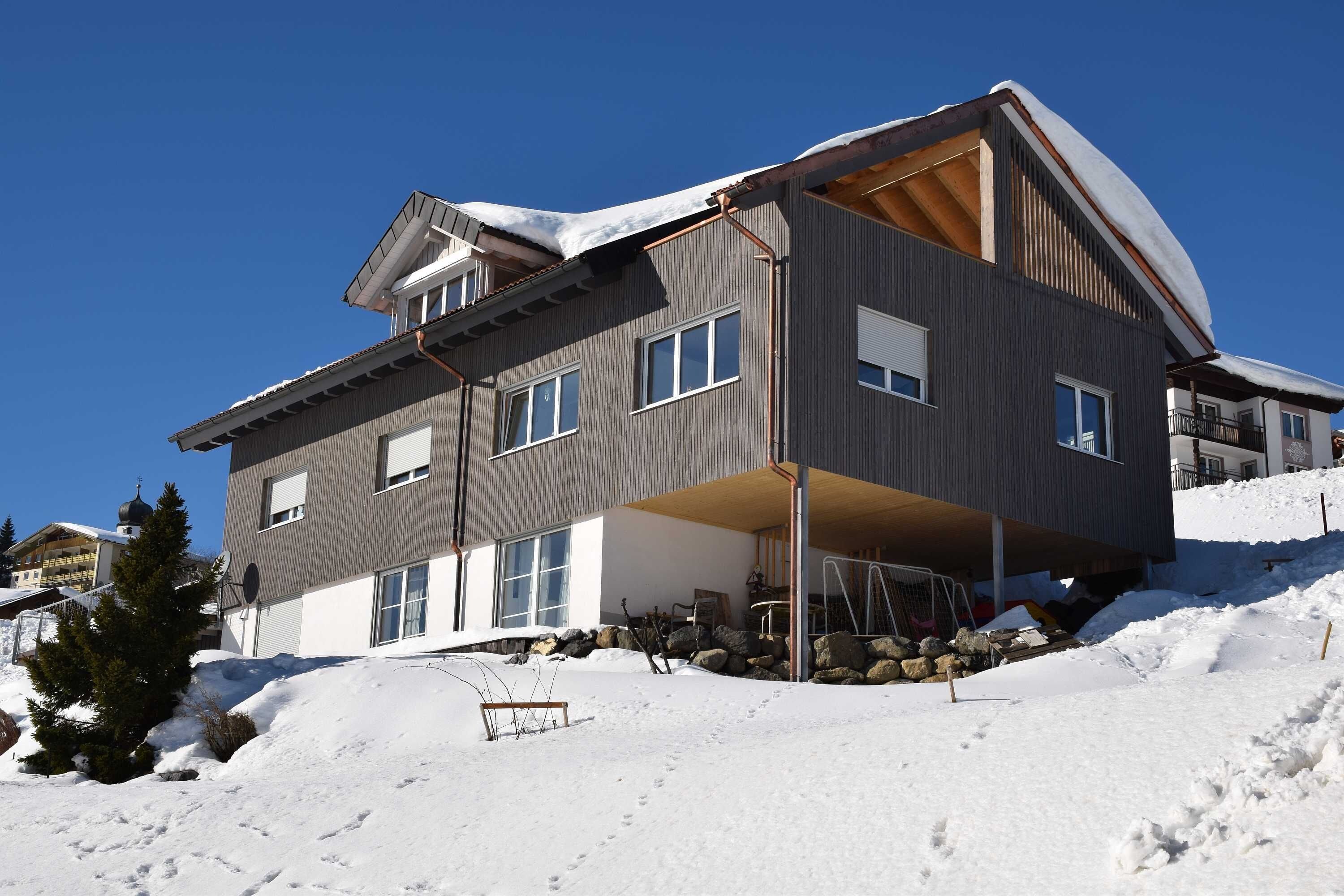 Un immeuble à plusieurs étages doté d’un espace extérieur couvert, entouré de neige.