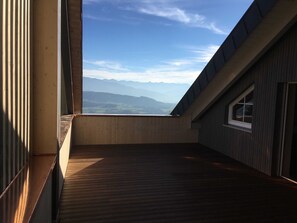 A room with a sloped ceiling and a view of distant mountains.
