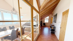A spacious room with a large sliding glass door leading to a terrace, a dining area with a table and chairs, and a kitchen area with a stove and sink.