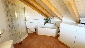 Une salle de bain avec une douche à parois de verre, des toilettes, une baignoire et un meuble de rangement.