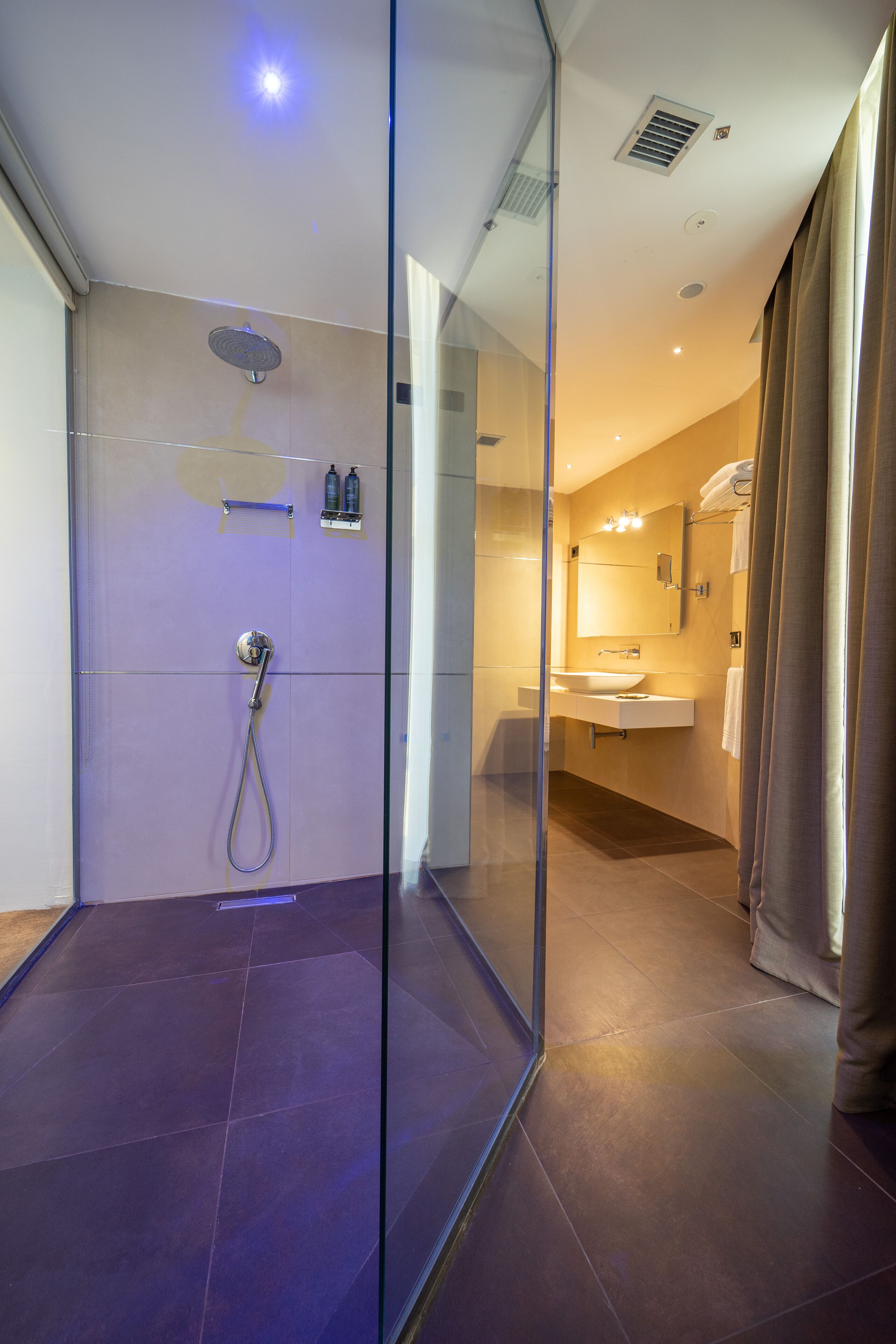 A modern bathroom with a glass shower enclosure, a vanity with a mirror, and a towel rack.