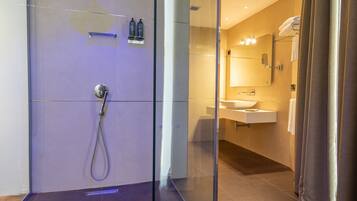 A modern bathroom with a glass shower enclosure, a vanity with a mirror, and a towel rack.