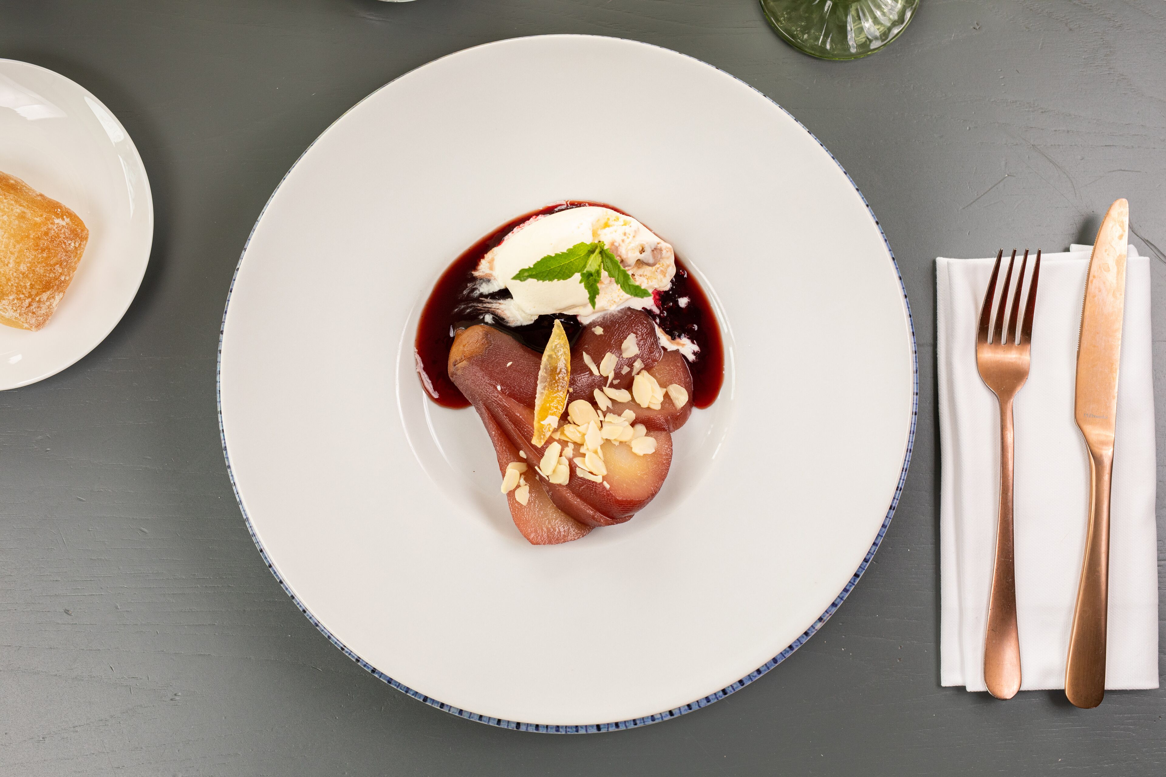 Postre en un plato blanco con borde azul, acompañado de un tenedor y cuchillo sobre una servilleta.