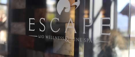 Un ventanal de vidrio con el logotipo y el nombre 'Escape Bio Wellness & Wine Spa'.