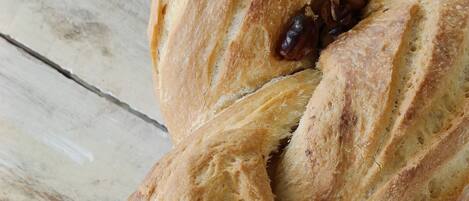 Une miche de pain tressé aux raisins, posée sur une surface en bois.