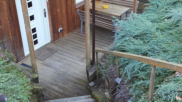 A wooden staircase leading to a covered outdoor area with a bench and a table.