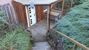 A wooden deck with a bench and a door leading to a building.