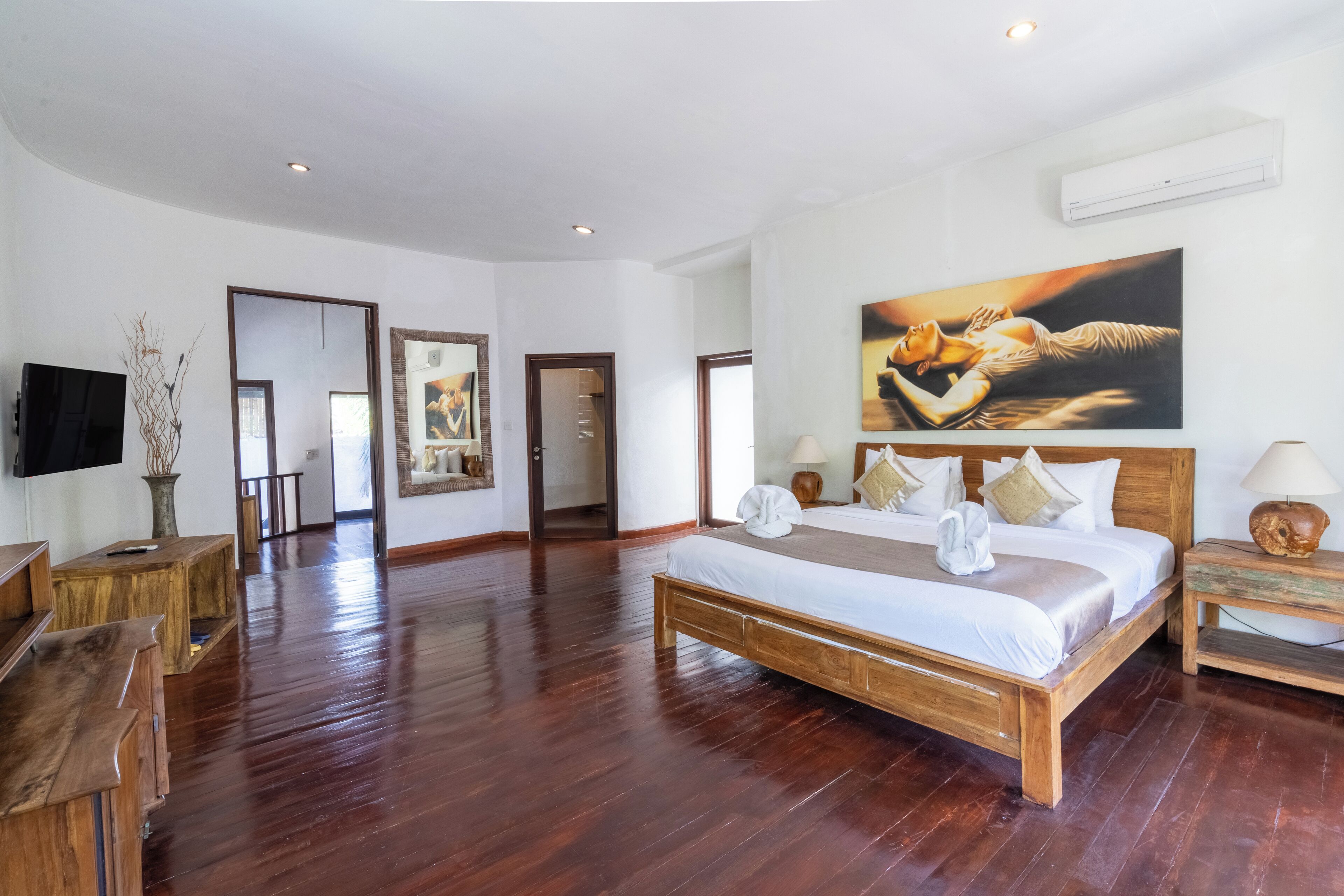 Um quarto espaçoso com uma cama grande, mobiliário de madeira e um quadro na parede.