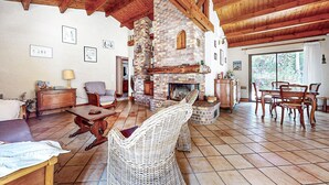A cozy living room with a stone fireplace, wooden beams, and a dining area with wicker furniture. - 2 bedroom stunning home in La Faute sur Mer (La Faute sur Mer)