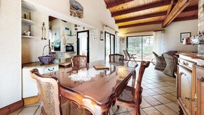 A spacious dining area with a wooden table and chairs, a kitchen with a TV, and a view of the outdoors. - 2 bedroom stunning home in La Faute sur Mer (La Faute sur Mer)