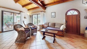 A cozy living room with wicker furniture, a wooden ceiling, and a large window. - 2 bedroom stunning home in La Faute sur Mer (La Faute sur Mer)