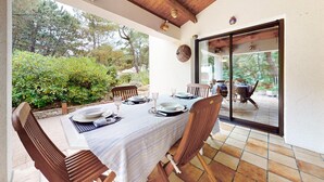 An outdoor patio with a table set for dining, surrounded by wooden chairs, and a view of the garden and trees. - 2 bedroom stunning home in La Faute sur Mer (La Faute sur Mer)