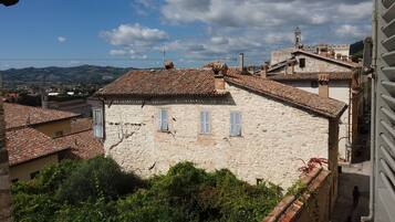 A stone building with a tiled roof, a bell tower, and a view of distant hills.