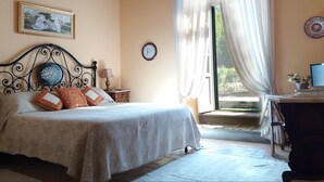 Un dormitorio con una cama, una mesita de noche, un reloj y una ventana con cortinas.