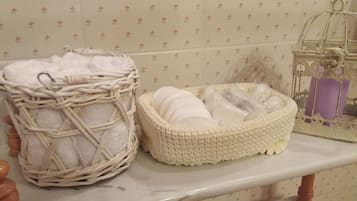 A bathroom with a marble countertop, a wicker basket, and a crocheted basket with toiletries.