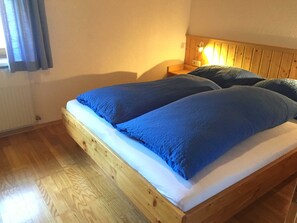 Una cama doble con cabecera de madera, una mesita de noche y una ventana con cortinas.