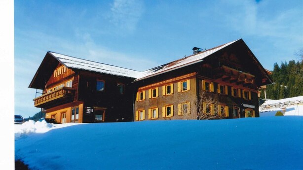 Un gran edificio de madera con múltiples ventanas y balcones, rodeado de nieve.
