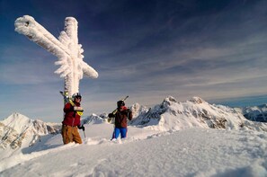 Eine verschneite Berglandschaft mit einer Person, die auf einem mit Schnee bedeckten Gipfel steht.