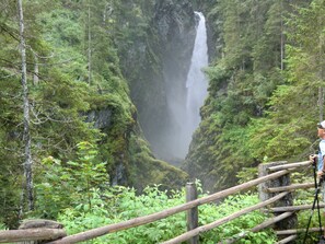 A waterfall surrounded by lush greenery and a wooden viewing platform. - Apartment 3 - Landhaus Dengg (Gerlos)
