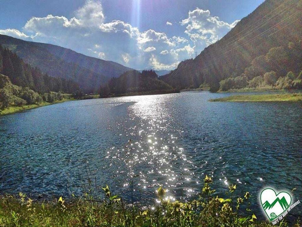A serene lake surrounded by mountains with a clear sky.