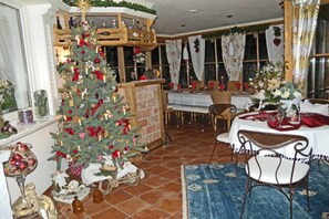 A dining area with a Christmas tree, a fireplace, and a table set for a meal. - Apartment 3 - Landhaus Dengg (Gerlos)
