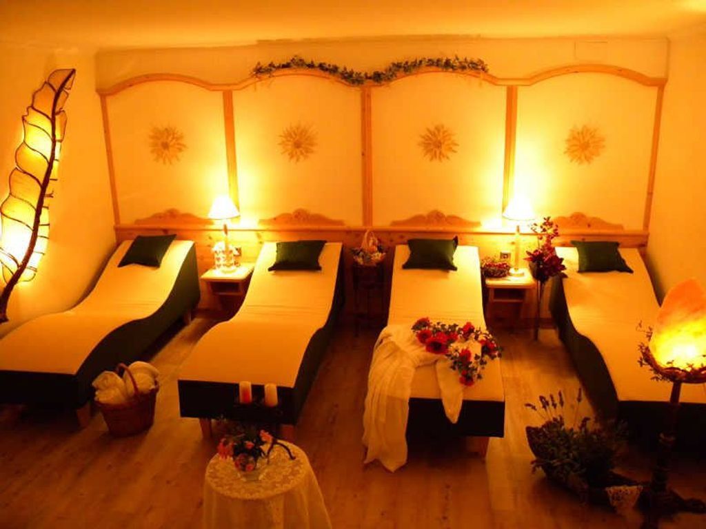 A room with two beds, each with a nightstand and a lamp.