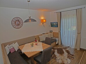 A cozy living room with a sofa, a wooden table, a TV, a clock, and a fur rug. - Apartment 3 - Landhaus Dengg (Gerlos)