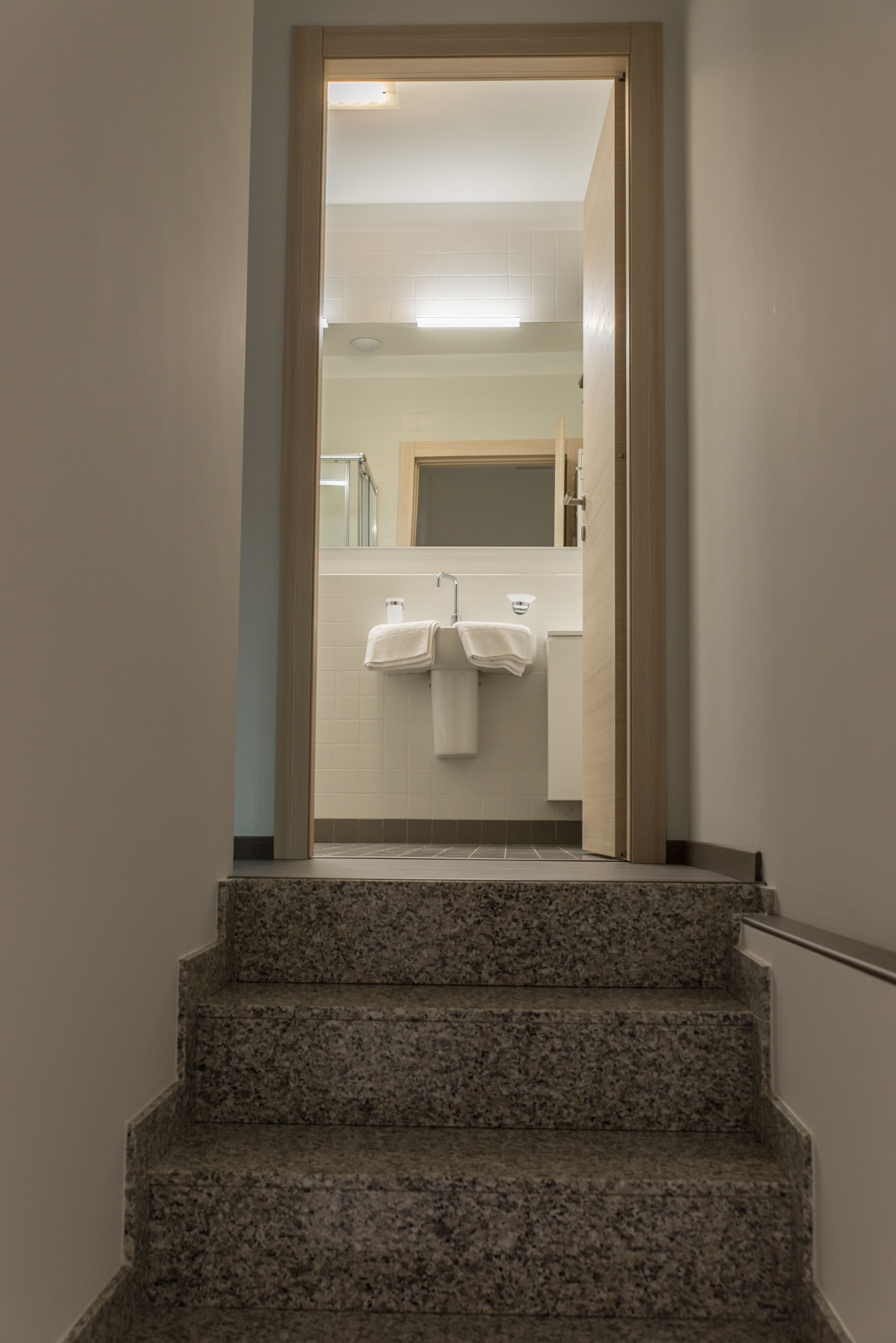A staircase leading to a bathroom with two white towels hanging on a rack.