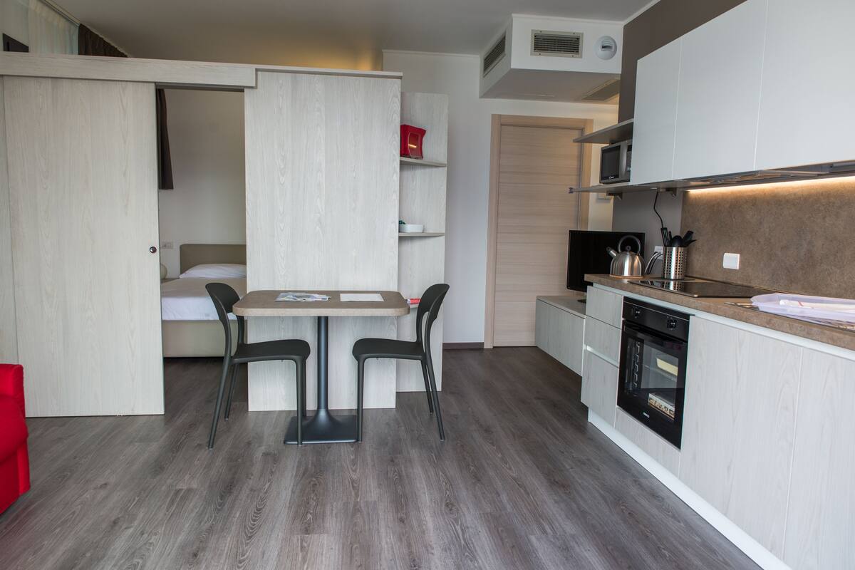 A compact kitchen with a dining area, built-in microwave, and oven.