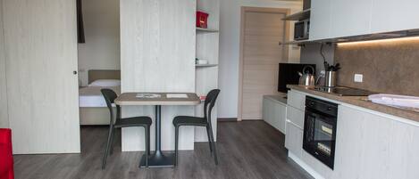 Cocina compacta con comedor, microondas empotrado y horno.