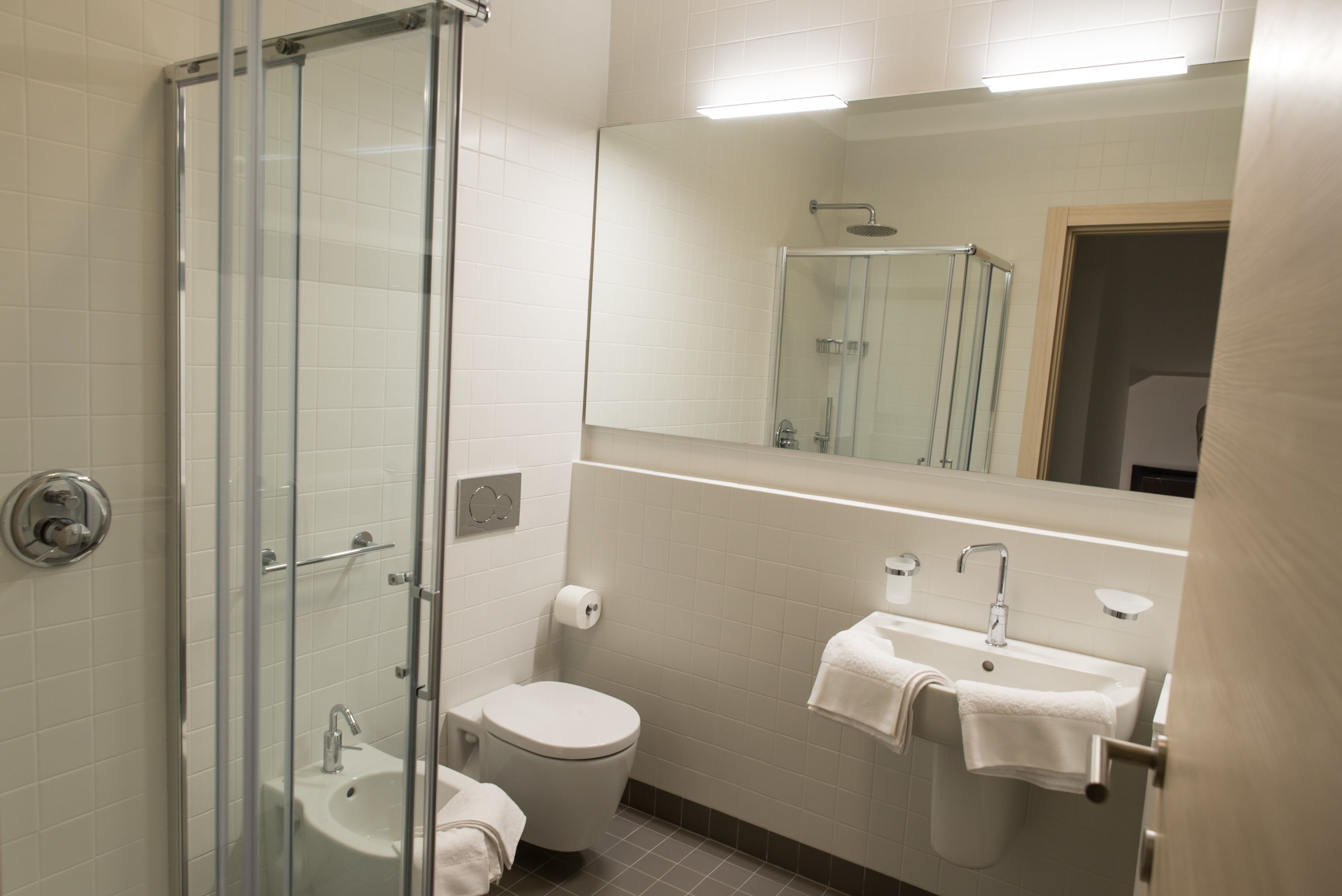 Ein modernes Badezimmer mit einer Duschkabine, einer Toilette und einem Waschbecken mit Handtuchhalter.