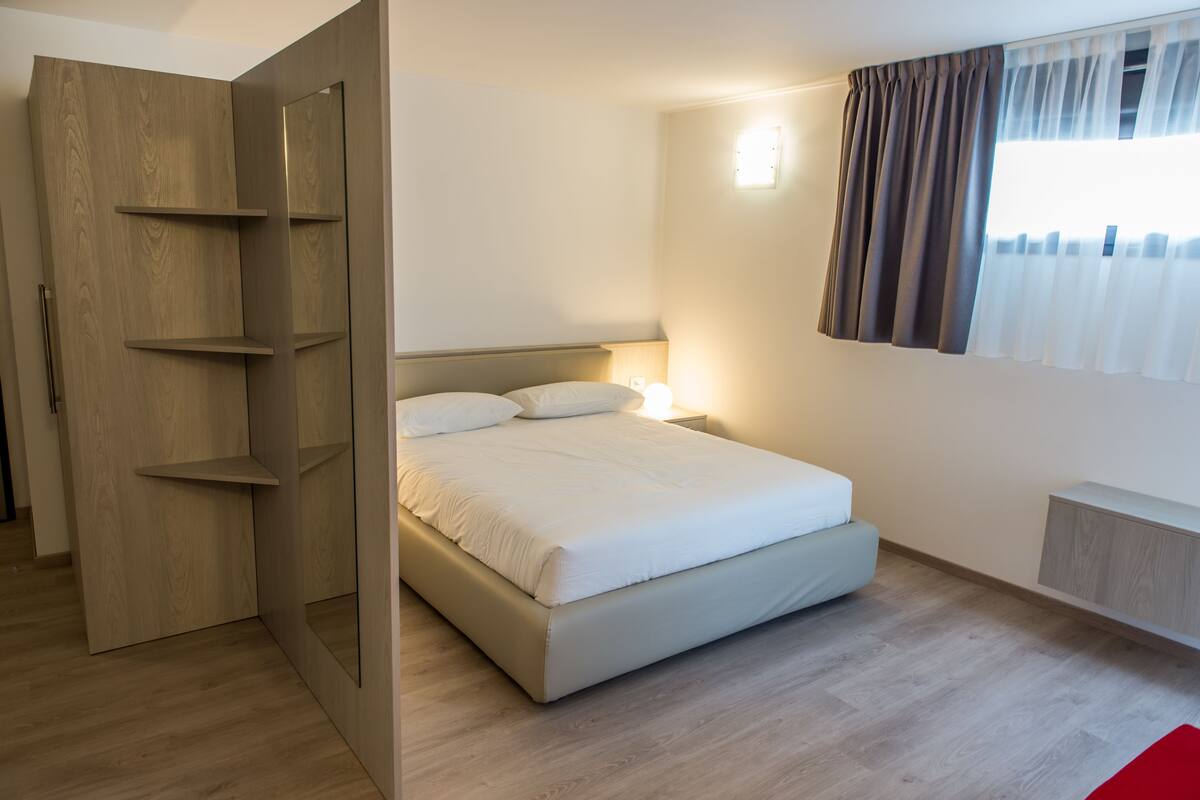 A bedroom with a bed, bedside table, and a wardrobe.