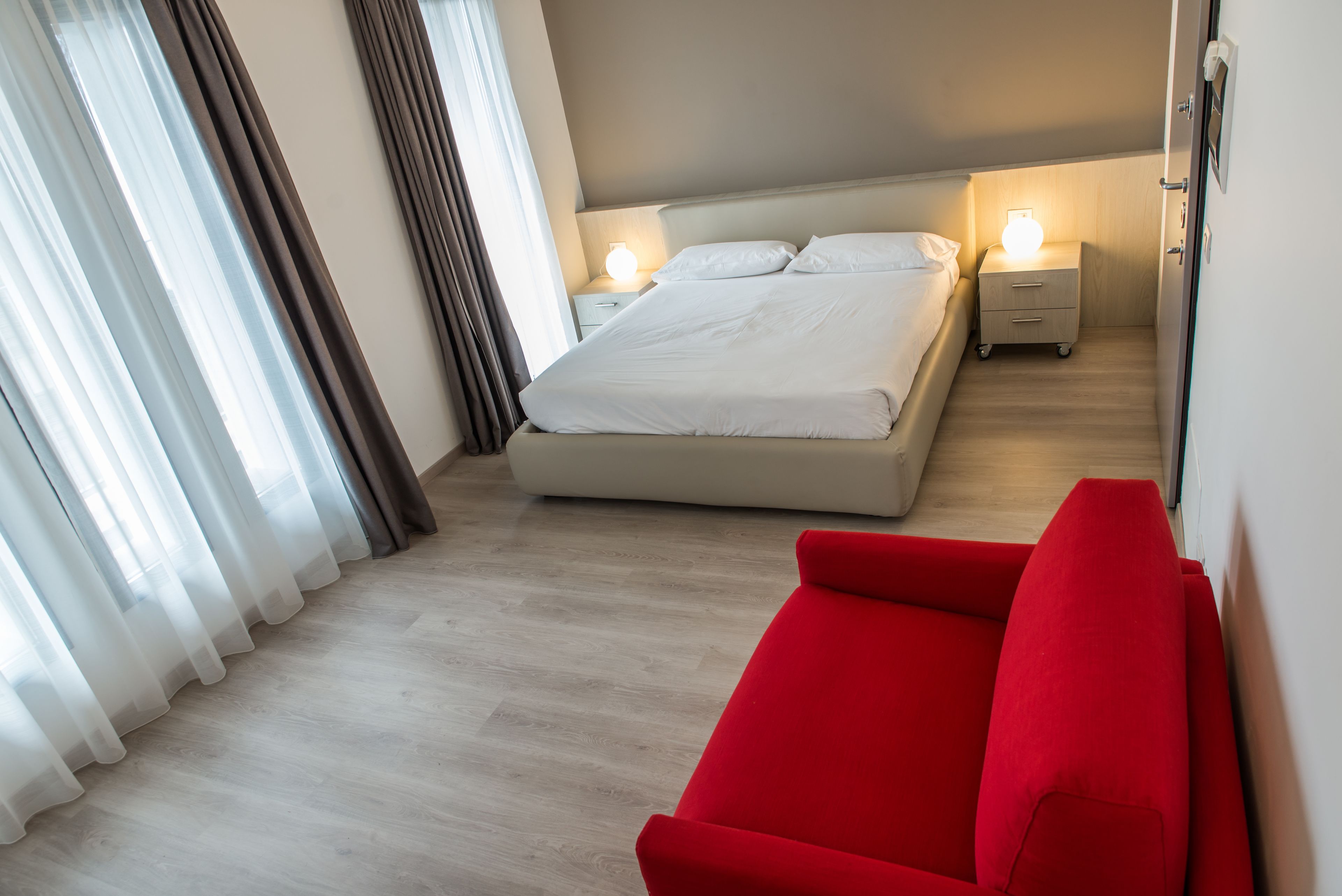 A bedroom with a bed, bedside tables, and a red sofa.