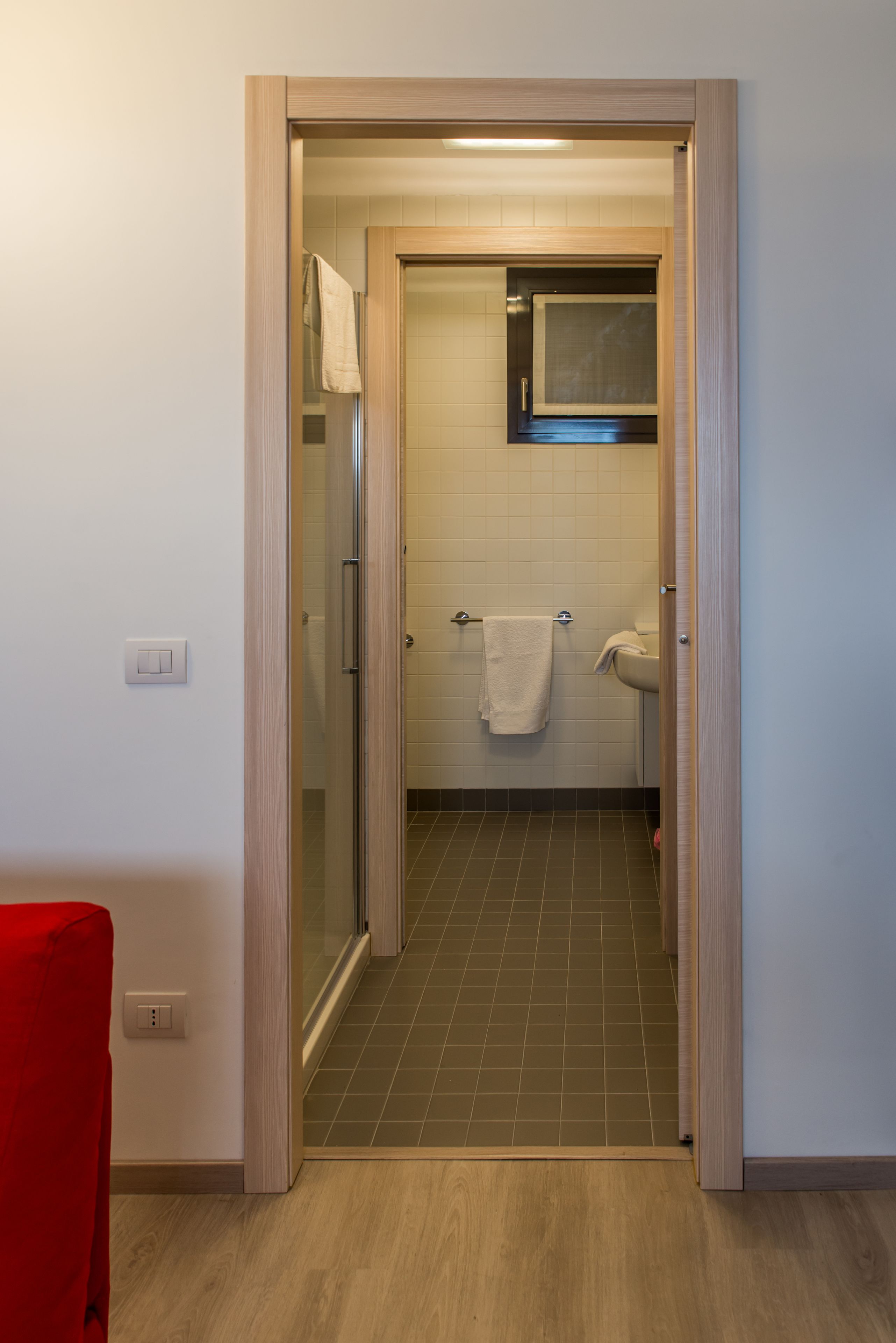 A bathroom with a glass shower door, a white sink, and a towel hanging on the wall.
